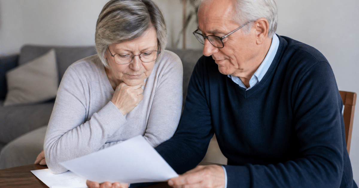 Couple senior assis examinant documents contrat assurance immobilier