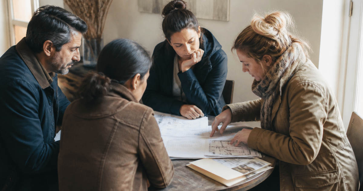 Groupe autour table examinant dossiers logement assis