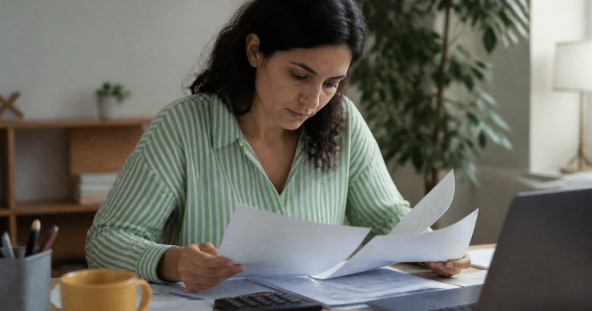 Personne consultant documents fiscaux sur bureau avec calculatrice visible