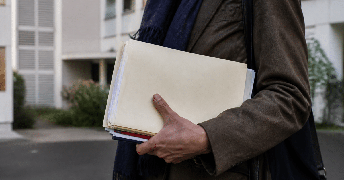 Mains tenant dossier administratif devant immeuble résidentiel