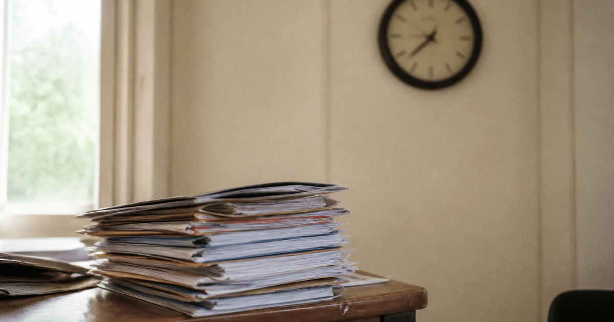 Dossier papier empilé sur bureau avec horloge murale