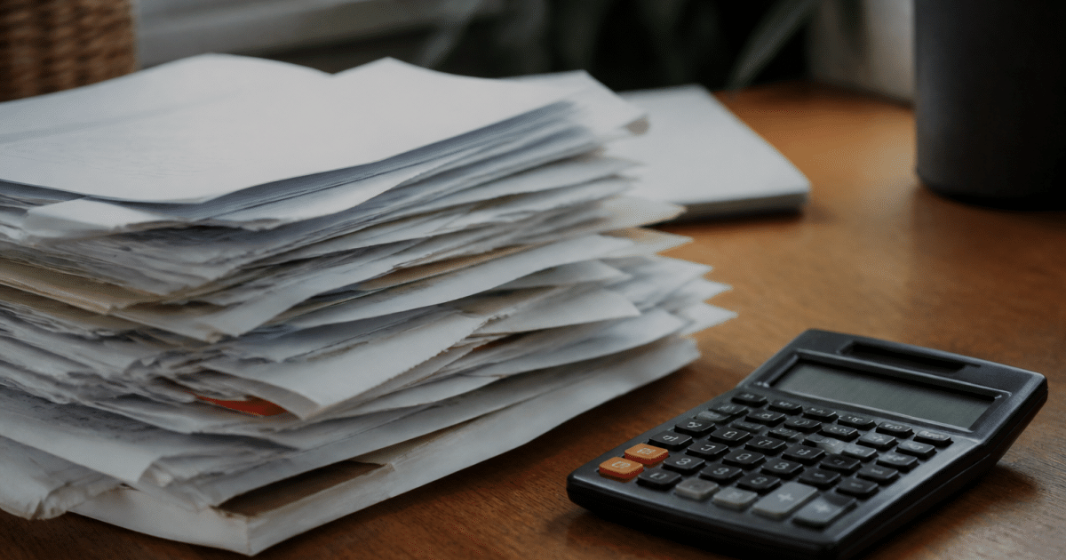 Factures papier empilees sur bureau pres calculatrice