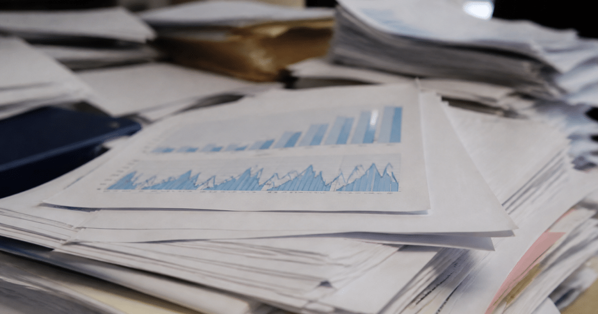 Documents financiers empiles sur bureau montrant graphiques hausse impots