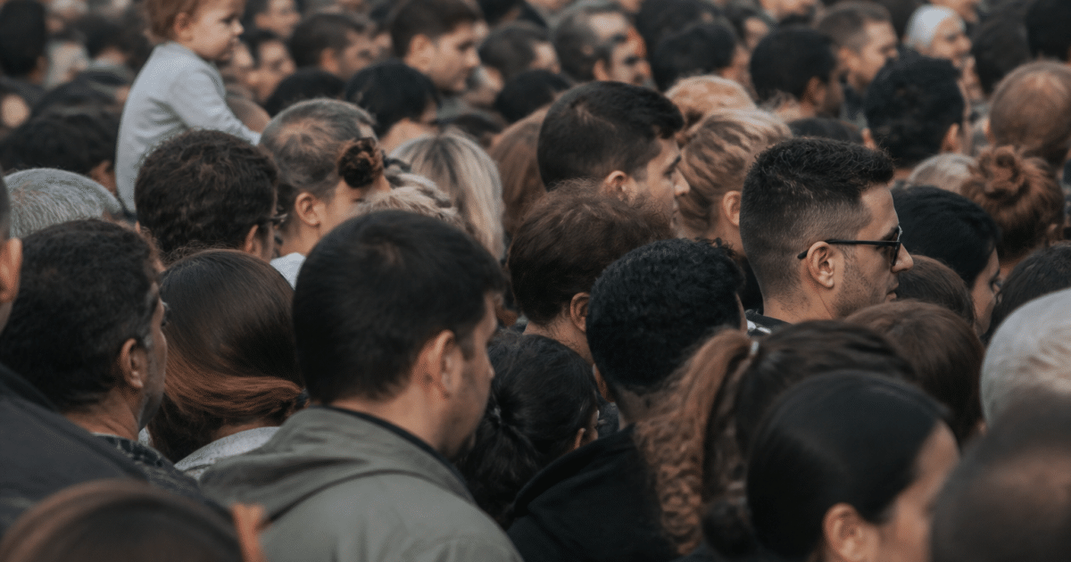 Foule dense de personnes debout serrees dans espace urbain
