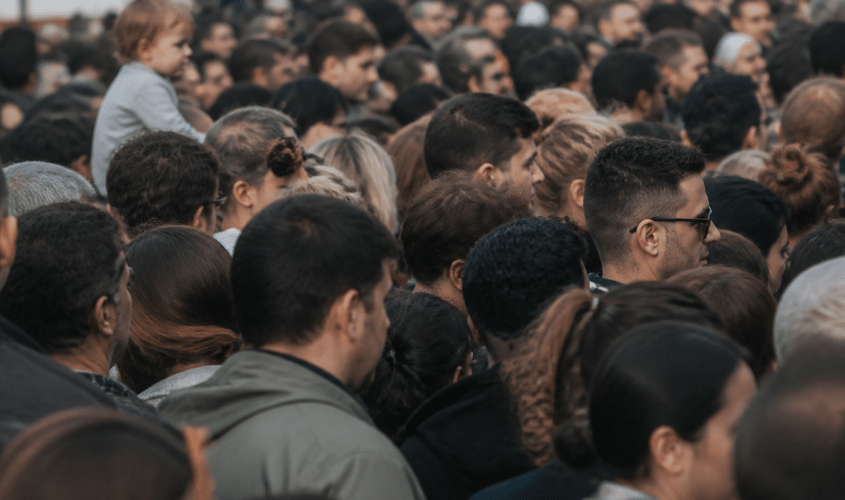 Foule dense de personnes debout serrees dans espace urbain