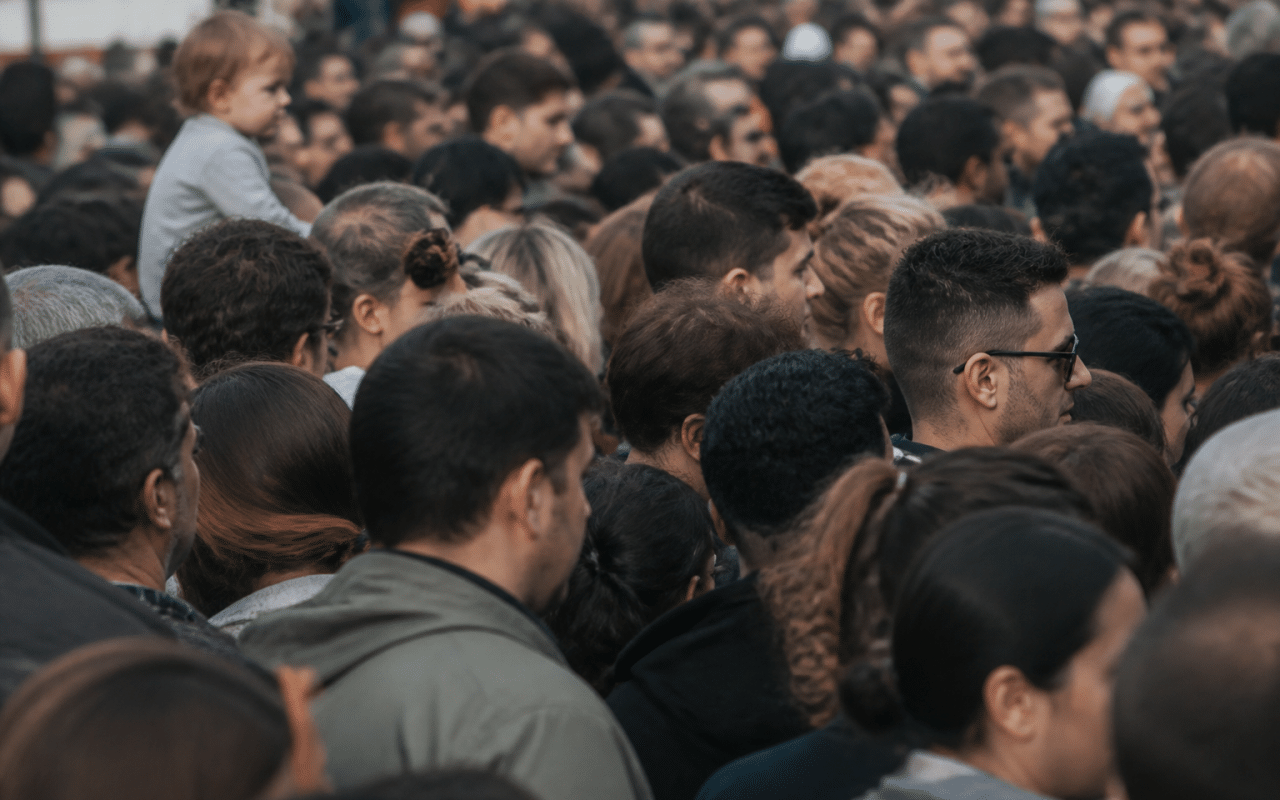Foule dense de personnes debout serrees dans espace urbain