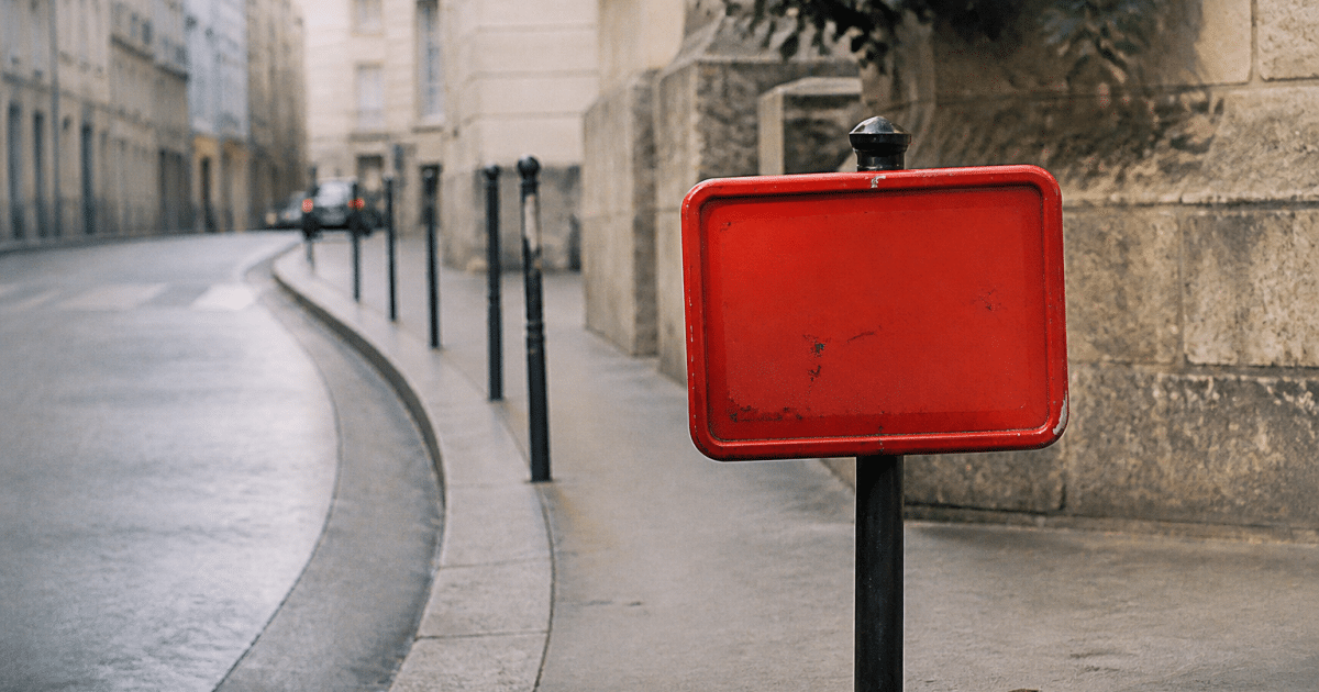 Panneau d'avertissement rouge sur rue urbaine parisienne déserte