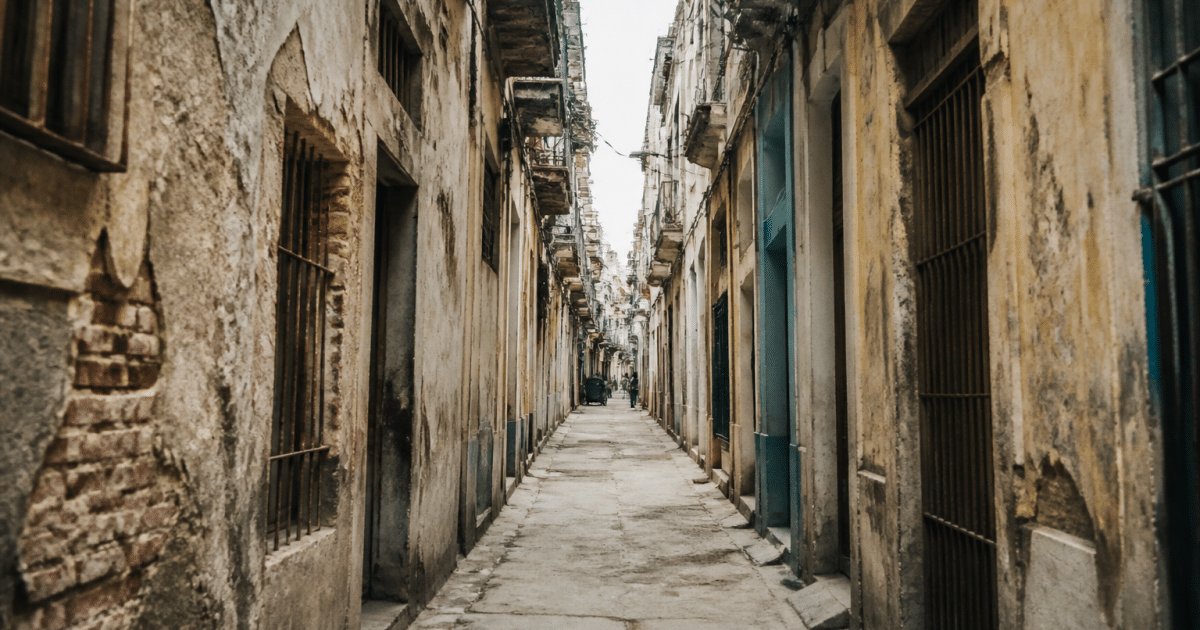 Rue urbaine étroite avec immeubles délabrés et façades usées.