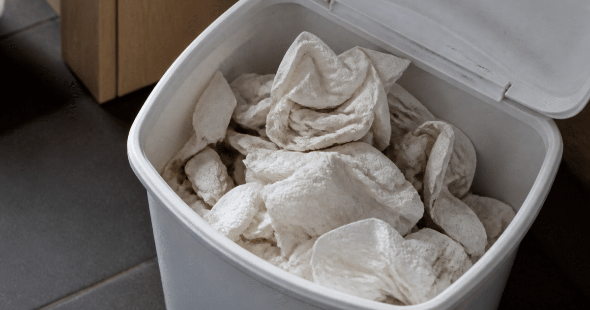 Serviettes usagees empilees dans bac recyclage blanc ouvert
